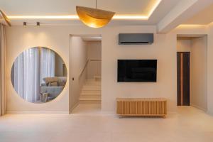 a living room with a round mirror and a tv at Costas Luxury Villas - Costa's Villa in Koskinou