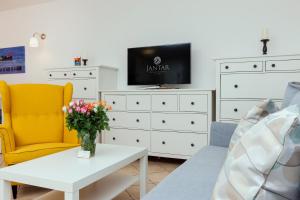 a living room with a tv and a couch and a table at Jantar Apartamenty - Wylotowa in Kołobrzeg