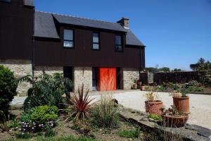una casa negra con una puerta roja y algunas plantas en Les Chambres d'hôtes de Kérasquer, en Lannilis
