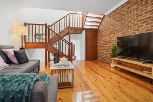 a living room with a couch and a brick wall at 2-Bedroom House-Near city center Good for 6 Guests in Sydney