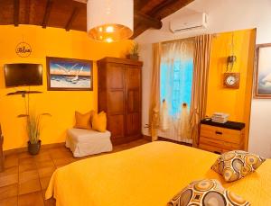 a yellow bedroom with two beds and a television at MOONIC83 Spiaggia Privata in Trevignano Romano
