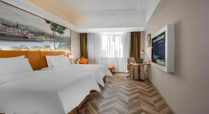 a hotel room with two beds and a flat screen tv at Vienna Hotel Tianjin Huaming in Tianjin