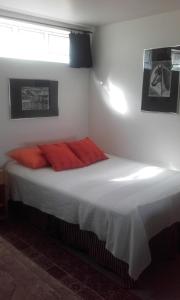 1 dormitorio con 1 cama con sábanas blancas y almohadas rojas en Námshestar en Kuludalsa