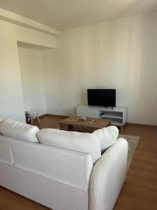 a living room with a white couch and a tv at appartement cosy tout équipé avec balcon in Châlette-sur-Loing