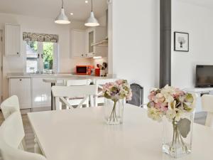 a white table with two vases of flowers on it at Wishing Well Cottage in Mathon