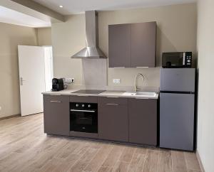 a kitchen with a stove and a sink and a refrigerator at Charmant T2 tout confort in Montignac