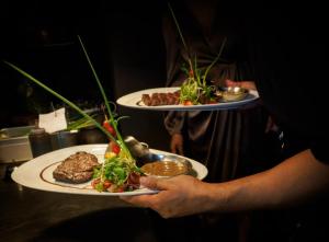 a person holding two plates with food on them at Oceanview Bungalows by EAT in Karon Beach