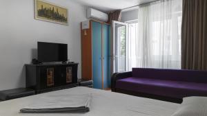 a room with a bed and a purple couch and a window at Garsoniera in Mangalia