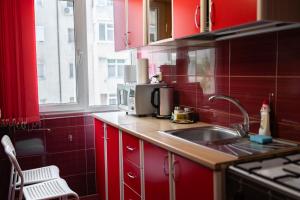 a red kitchen with a sink and a microwave at Garsoniera in Mangalia