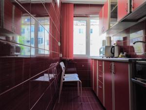 a kitchen with red cabinets and a chair in it at Garsoniera in Mangalia