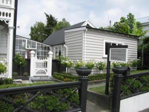 a white house with a fence in front of it at Historic Colenso Cottage in Napier