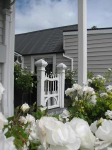 a white fence in front of a house with white flowers at Historic Colenso Cottage in Napier