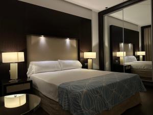 um quarto de hotel com uma cama grande e um espelho em Hotel Palacio Albacete & SPA em Albacete