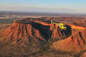 a yellow helicopter is flying over a mountain at Discovery Kings Canyon in Kings Canyon