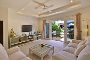 a living room with a white couch and a tv at The Gardens in Bangrak Beach