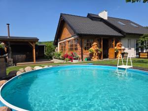 a house with a large swimming pool in front of it at Komfortowy Dom Całoroczny - sauna, jacuzzi, bilard in Tyłowo