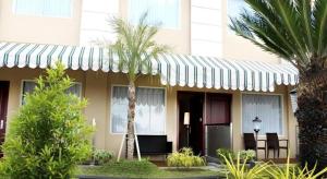 a building with a striped awning and palm trees at Grand Qin Hotel Syariah in Martapura
