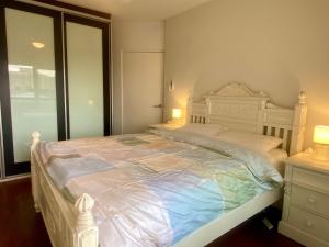 a bedroom with a large white bed with two lamps at Coastal Retreat- Beach, Lagoon & Cafes Just Steps from Your Door! in Narrabeen