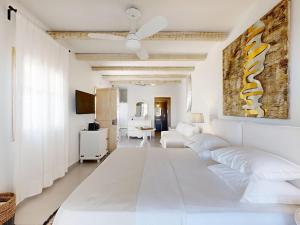 Una sala de estar con muebles blancos y un ventilador de techo. en Speires suites, en Iraklia