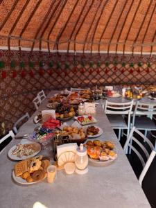 een lange tafel met borden met eten erop bij One Million Stars Yurt camp in Song-Kul +40 foto's