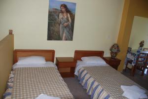 two beds in a room with a painting on the wall at Alessandro in Sidari