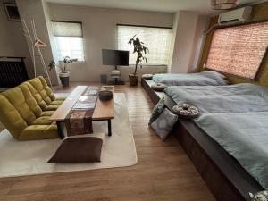 a bedroom with two beds and a table and a couch at SakuraPiso in Kagoshima +146 photos