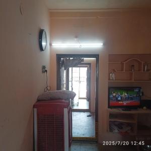 a living room with a television and a door to a hallway at Sai Home Stay in Narasaraopet