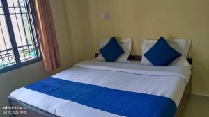 a bedroom with a bed with blue pillows and a window at Hotel Nanak bharmour manimahesh in Brāhmaur