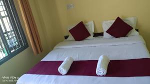 a white bed with red and white pillows on it at Hotel Nanak bharmour manimahesh in Brāhmaur