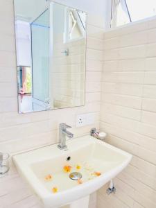 Un lavabo blanco en un baño con espejo. en Hikka Heaven Guest House, en Hikkaduwa