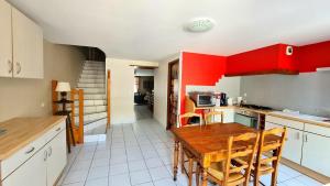 a kitchen with red cabinets and a wooden table at Gîte LE LOUP in Les Hautes-Rivières