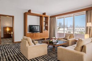 uma sala de estar com sofás e uma televisão em Jumeira Rotana – Dubai em Dubai