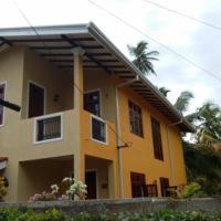 a yellow house with a palm tree in front of it at Villa Paragon in Negombo