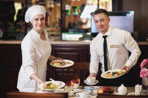 un hombre y una mujer sosteniendo platos de comida en Admiral Hotel, en Sevastopol