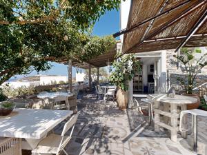 Un patio con mesas y sillas blancas y árboles. en Speires suites, en Iraklia
