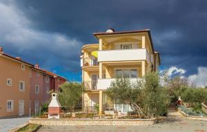 a yellow and white building with a cloudy sky at Apartment Ivana 2435 in Malinska