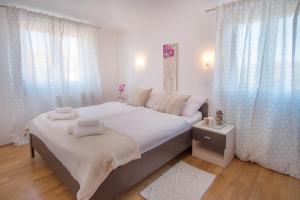 a white bedroom with a large bed with white curtains at Apartment Ivana 2435 in Malinska