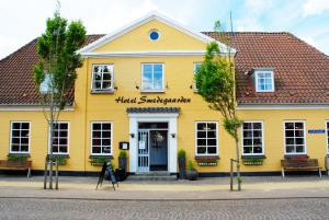 ein gelbes Gebäude mit einem Schild, das einen Dienstmädchen-Supermarkt liest in der Unterkunft Hotel Smedegaarden in Lem