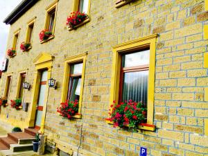 ein Backsteingebäude mit roten Blumen in Fensterkästen in der Unterkunft ARB Pension GmbH in Herchsheim