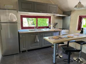 une cuisine avec un réfrigérateur en acier inoxydable et une table dans l'établissement La Maison aux Volets Rouges, à La Ferté-Beauharnais