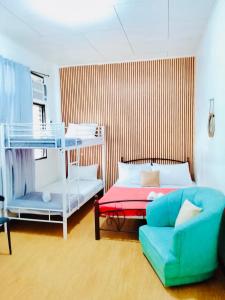 a bedroom with a bunk bed and a couch at HOST HOMES - CASA ELIZA in Tacloban