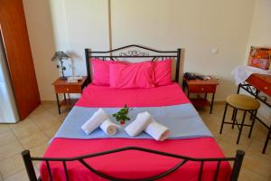 1 dormitorio con cama roja y almohadas rosas en Korali, en Almiropótamos