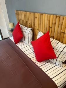 a bed with two red pillows on top of it at Pink House Guest House Lamai - Pool & Sea View in Lamai