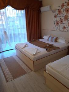 two beds in a hotel room with a window at Семеен хотел Вермона in Primorsko +22 photos