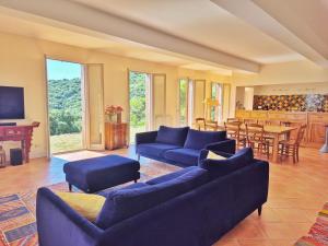 una gran sala de estar con sofás azules y una cocina. en Mas d'en Selve Domaine d'exception avec vue Mer, en Argelès-sur-Mer