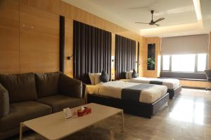 a hotel room with two beds and a couch at Hotel radiance in Bhilwara