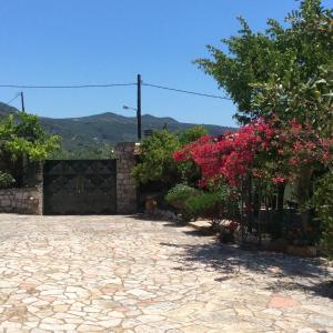 une allée avec un portail et des fleurs dans une cour dans l'établissement Santava House, à Akrogiali