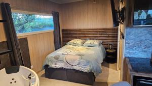 una camera con letto, finestra e vasca di Chalet bois pour 2 avec balnéo a Le Puy en Velay
