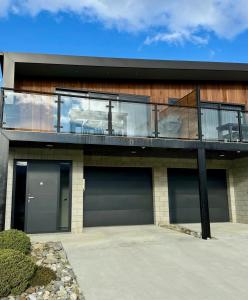 クロムウェルにあるHighlands Oasisのガレージドア2つとバルコニー付きの家