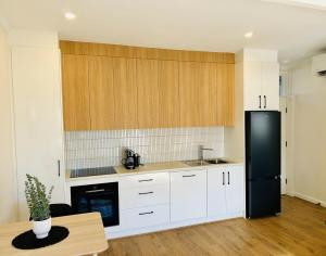 a kitchen with white cabinets and a black refrigerator at Stunning Modern Self-contained Apartment in Beaumont